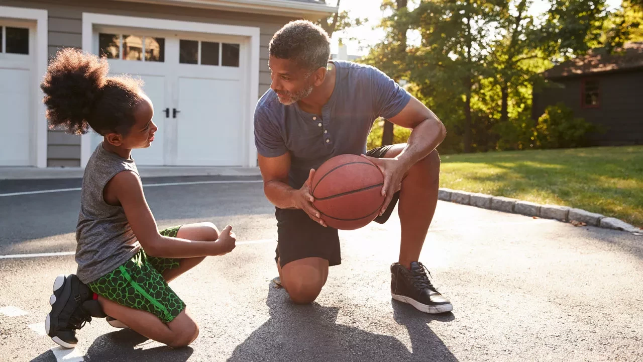 father and daughter playing basketball