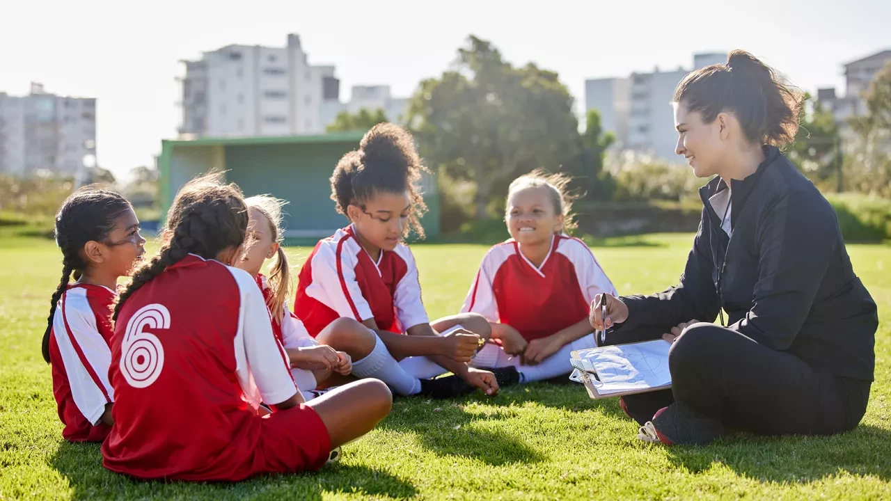 coach with youth soccer players sitting on the ground